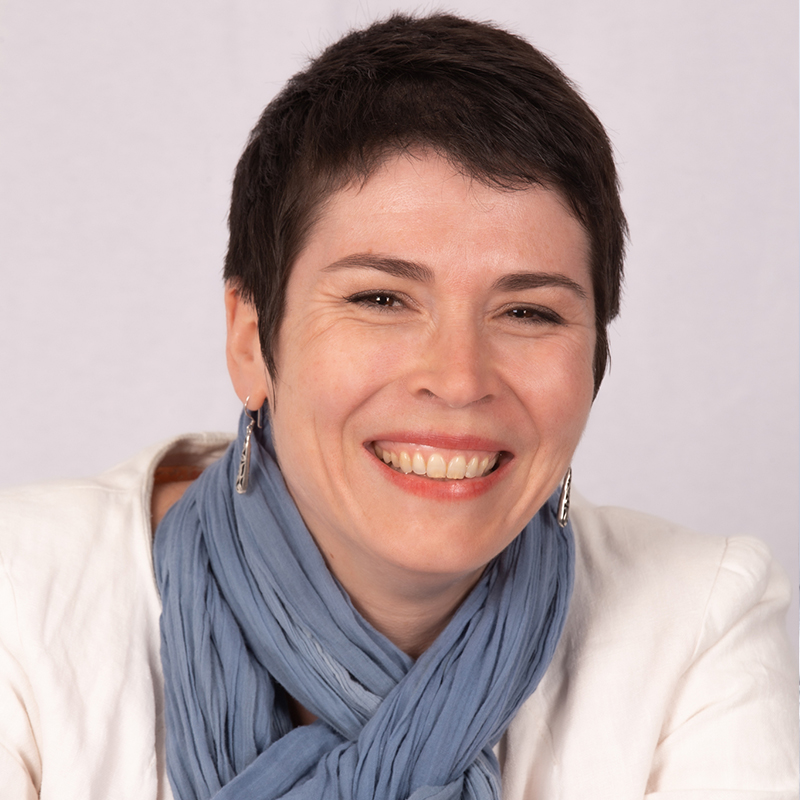 sourire d'une femme aux cheveux courts, haut blanc et écharpe bleue grise